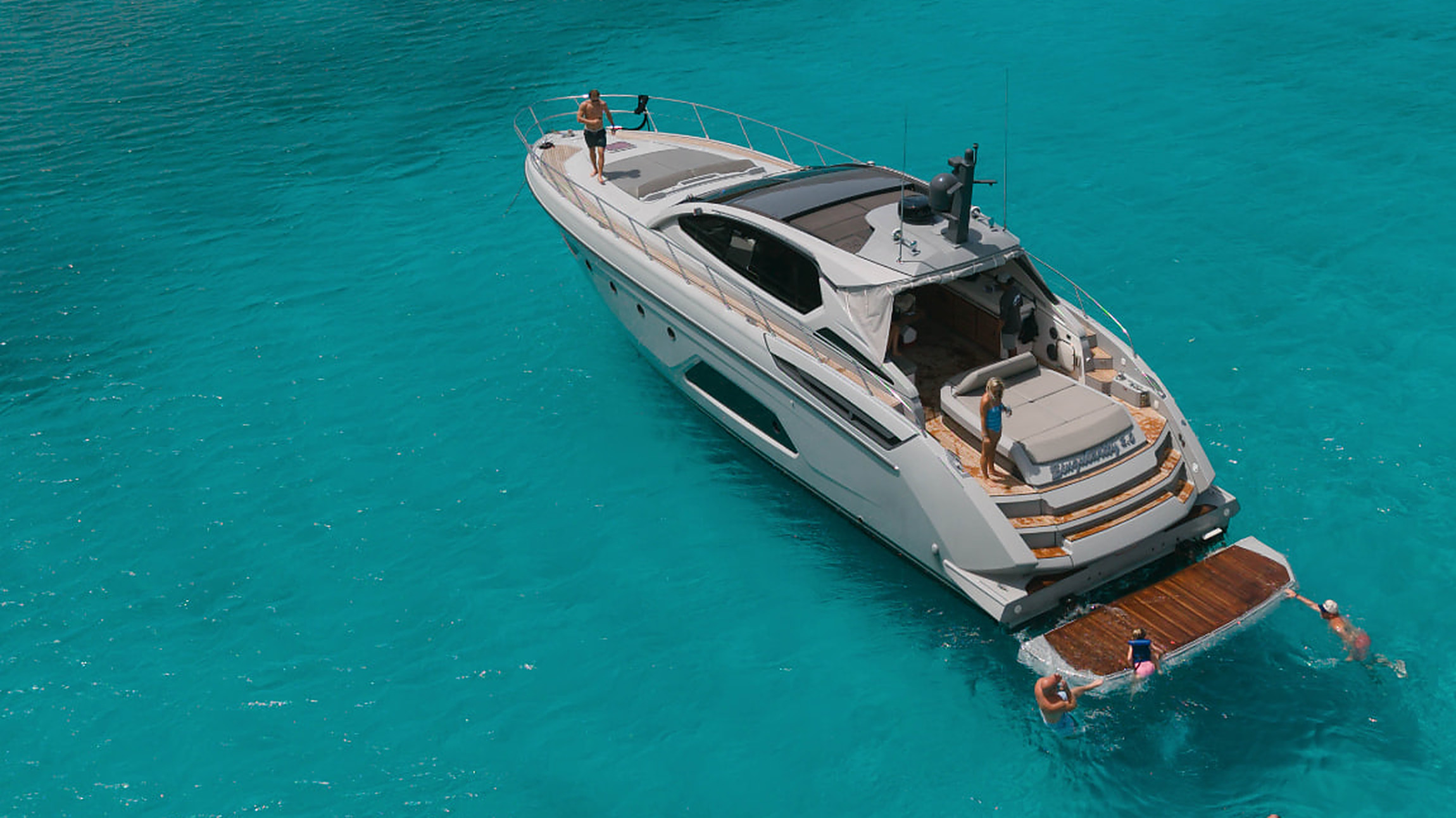 Guests swimming from a luxury motor yacht anchored in turquoise Caribbean water